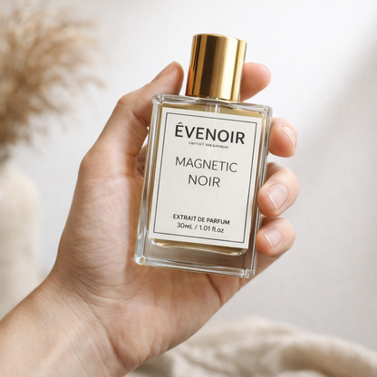 Hand holding Magnetic Noir extrait de parfum bottle with gold cap, 30ml size