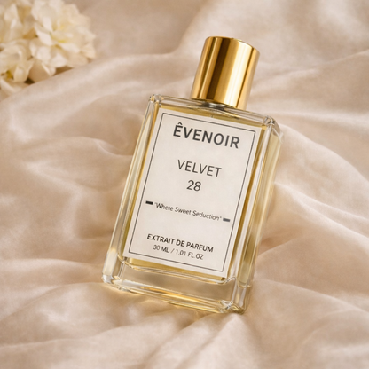 Transparent glass perfume bottle with gold cap labeled Velvet 28 on soft beige fabric