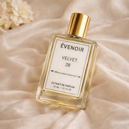 Transparent glass perfume bottle with gold cap labeled Velvet 28 on soft beige fabric